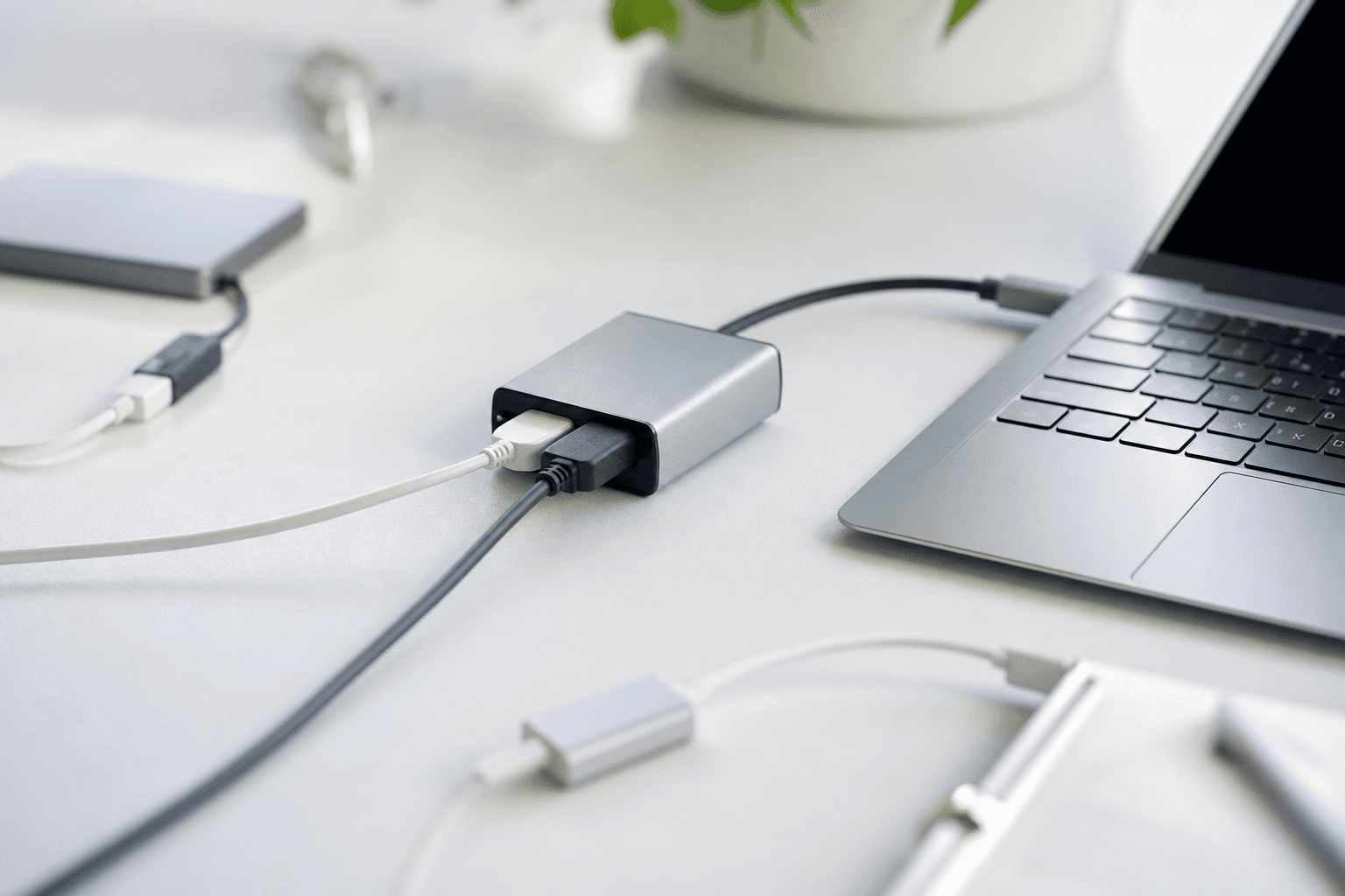 Soft abstract connection cables and adapters beside a laptop on a light desk